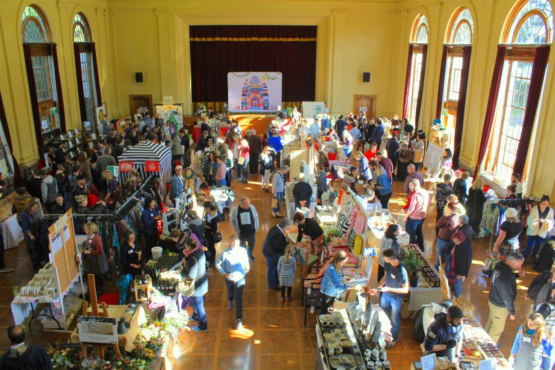 large crowd in indoor hall with many stalls