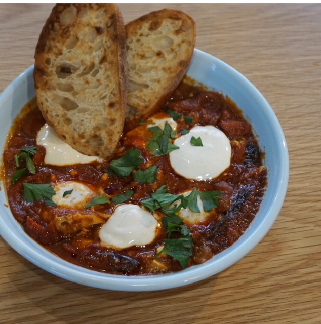 Spanish Shakshuka packed with cooked eggs in a tomato sugo with chorizo, feta & red peppers with toasted sourdough and coriander yoghurt. Photo: Sophia Brady