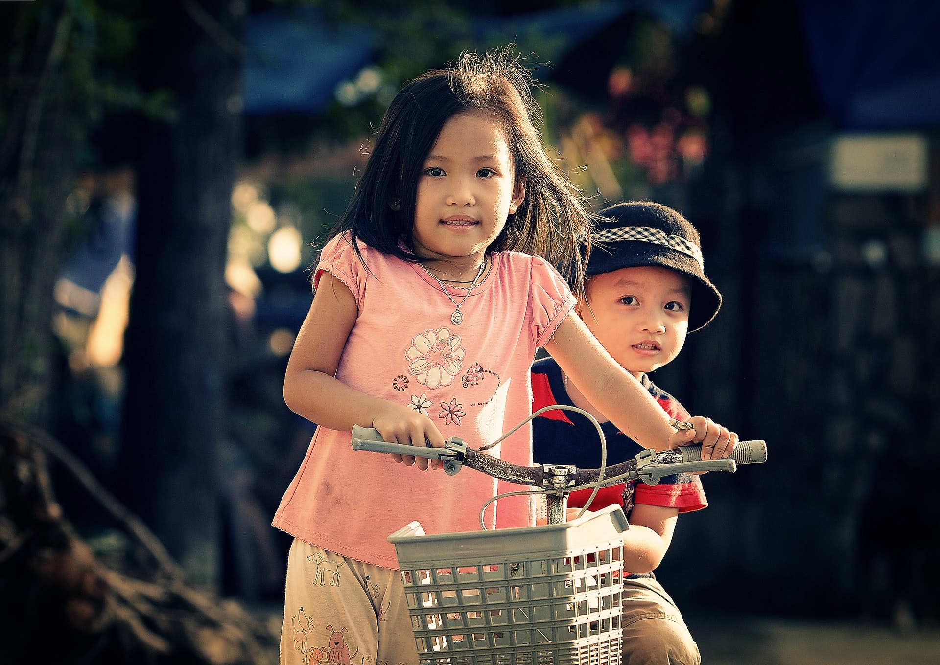 Young girl and young boy both on a bicycle and looking at the camera
