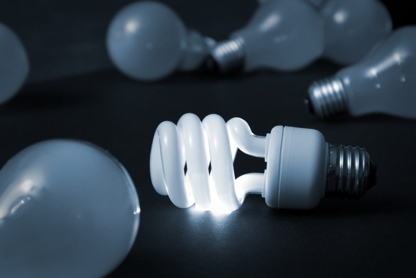 A new energy efficient CFL light bulb shines while the old ones fade into darkness.