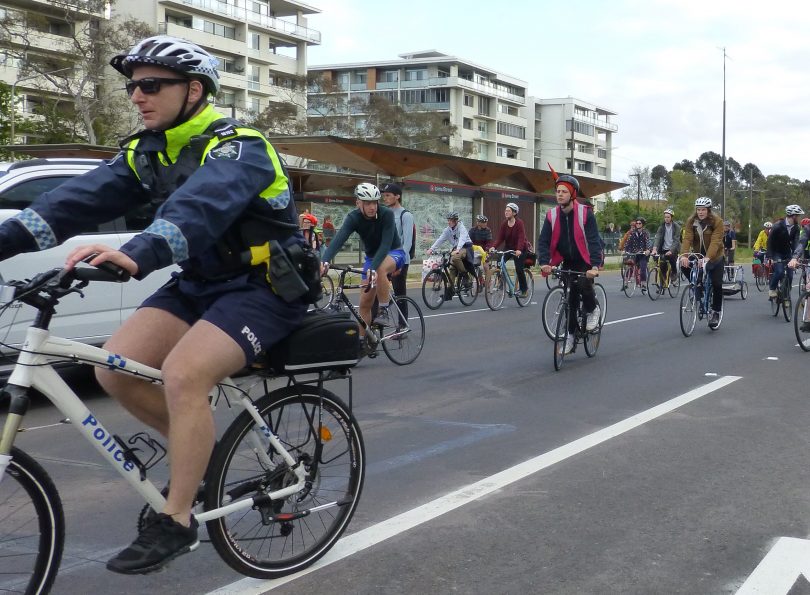 Policeman cyclist on bike with cyclists on Northbourne Avenue in Canberra.