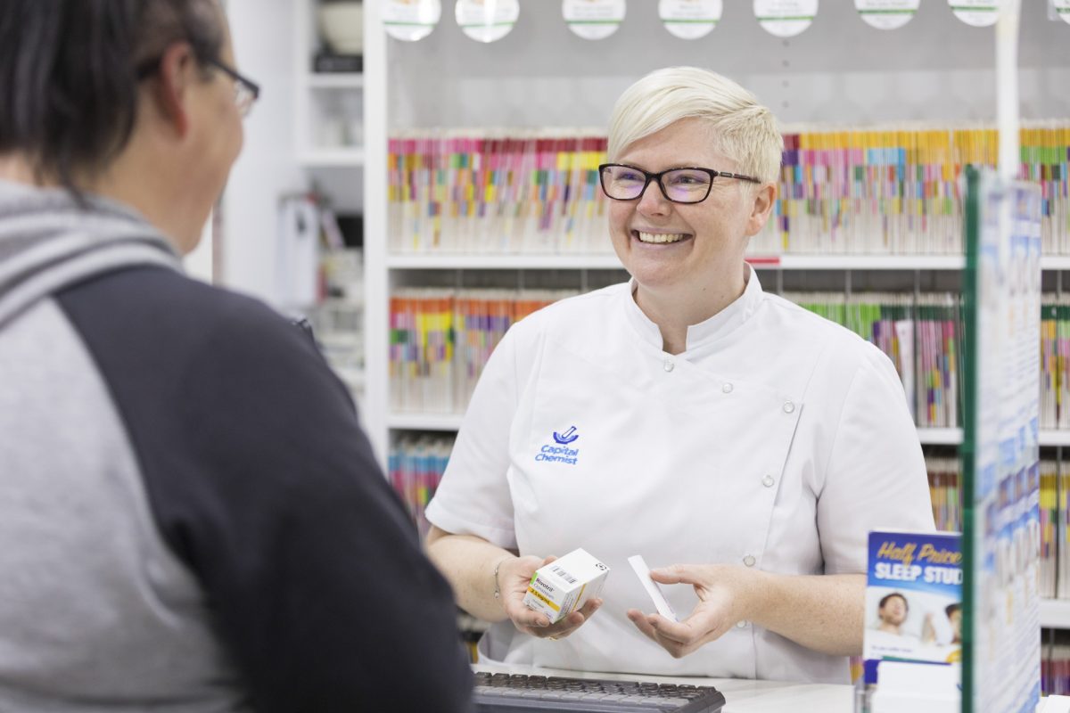 pharmacist speaking with a customer, holding medications