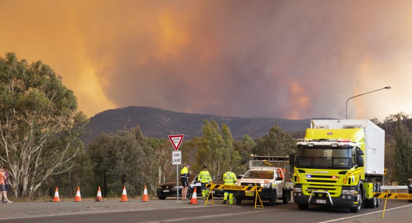 Orroral Valley bushfire burns in distance with road closure in foreground.