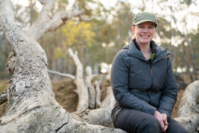 ANU student Belinda Wilson sitting on log at Mulligans Flat Nature Reserve.