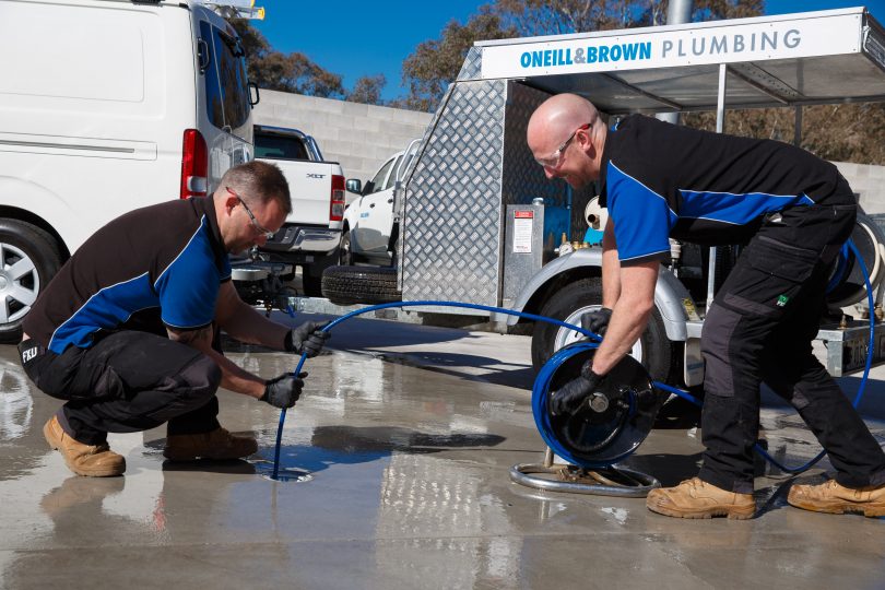 Plumbers feeding hose into drain.