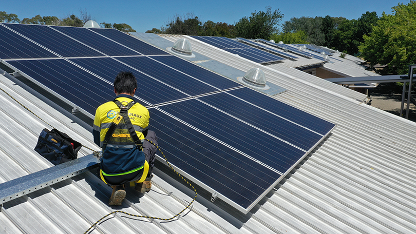 a person wearing hi-vis on a roof installing solar panels
