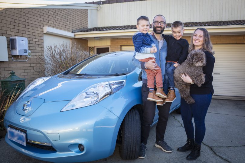 David Haynes and his family next to electric vehicle in driveway