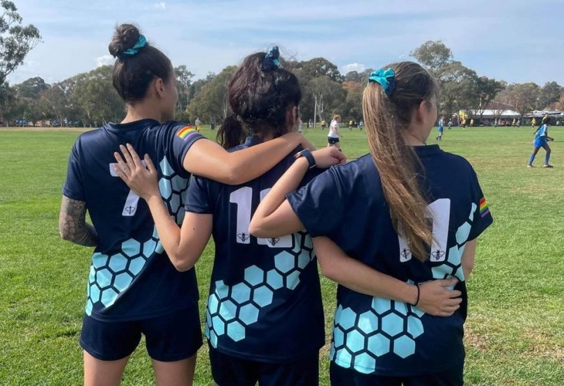 Three South Canberra Football Club players linking arms