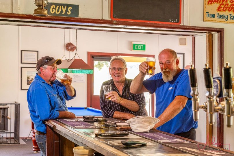 three men drinking beer at a pub bar