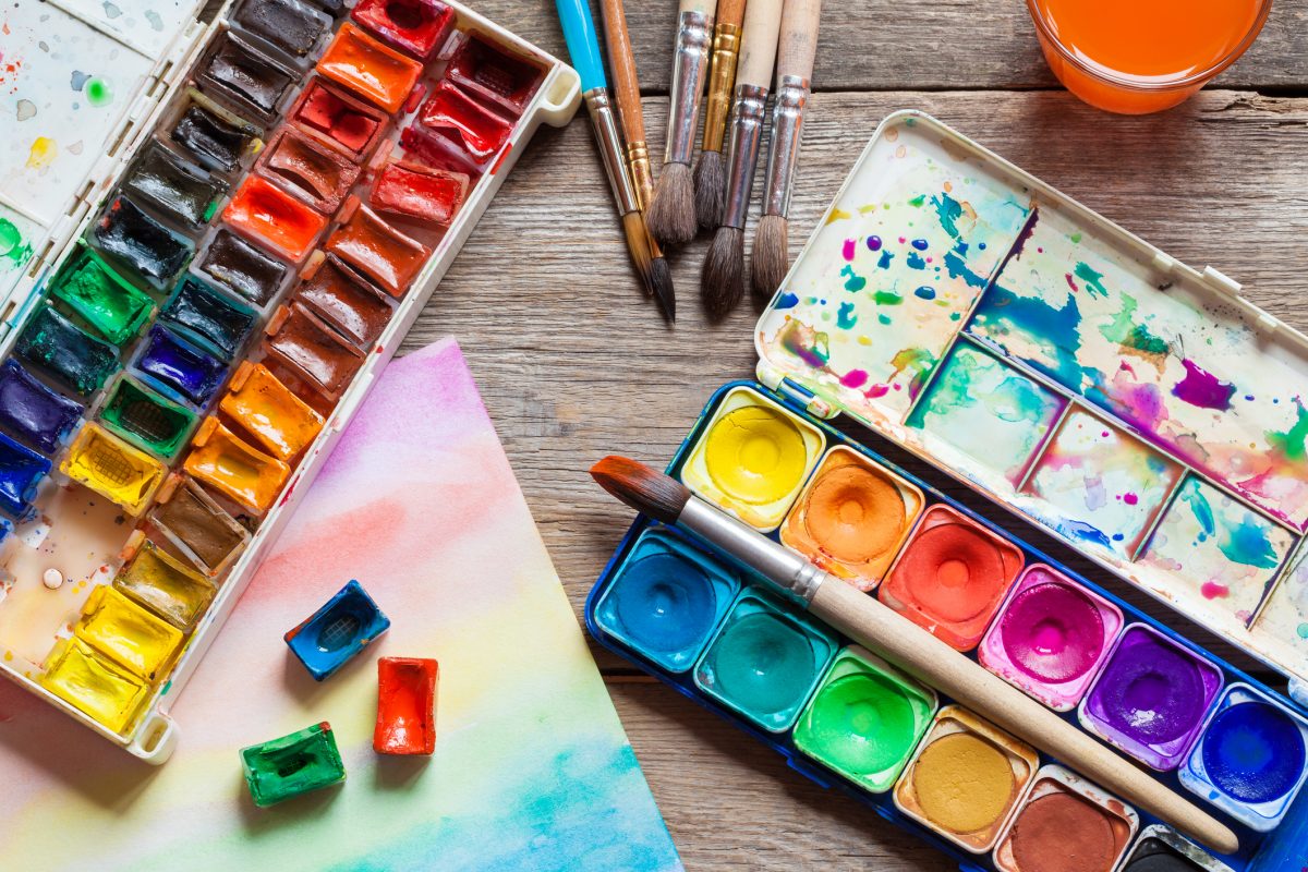 Set of watercolor paints, brushes for painting and paper sheet of painting on old wooden background