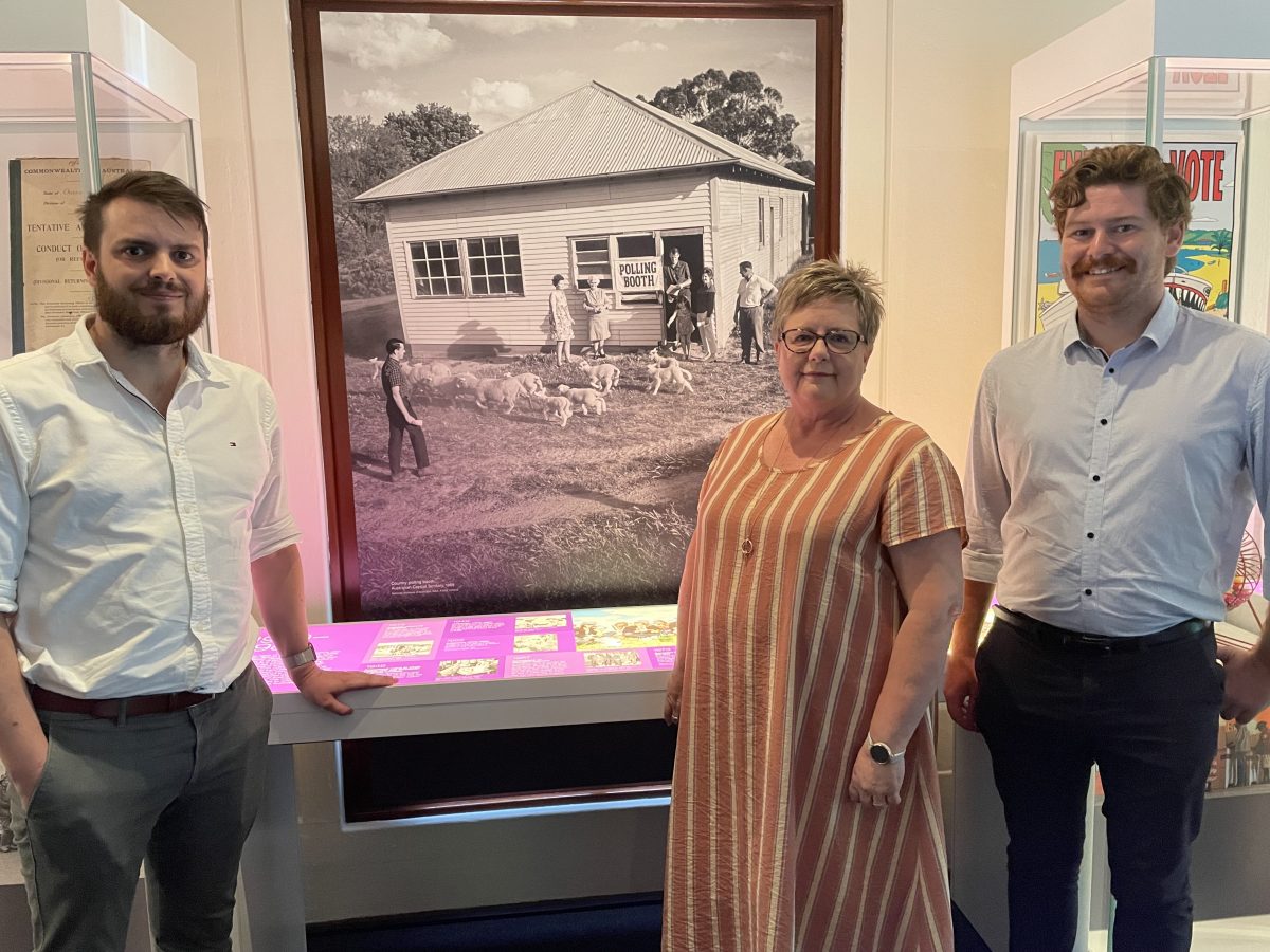 THree people in front of old polling booth picture.
