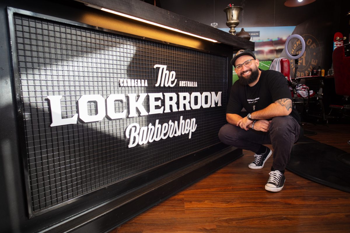 Man crouching in front of The Locker Room Barbershop reception desk