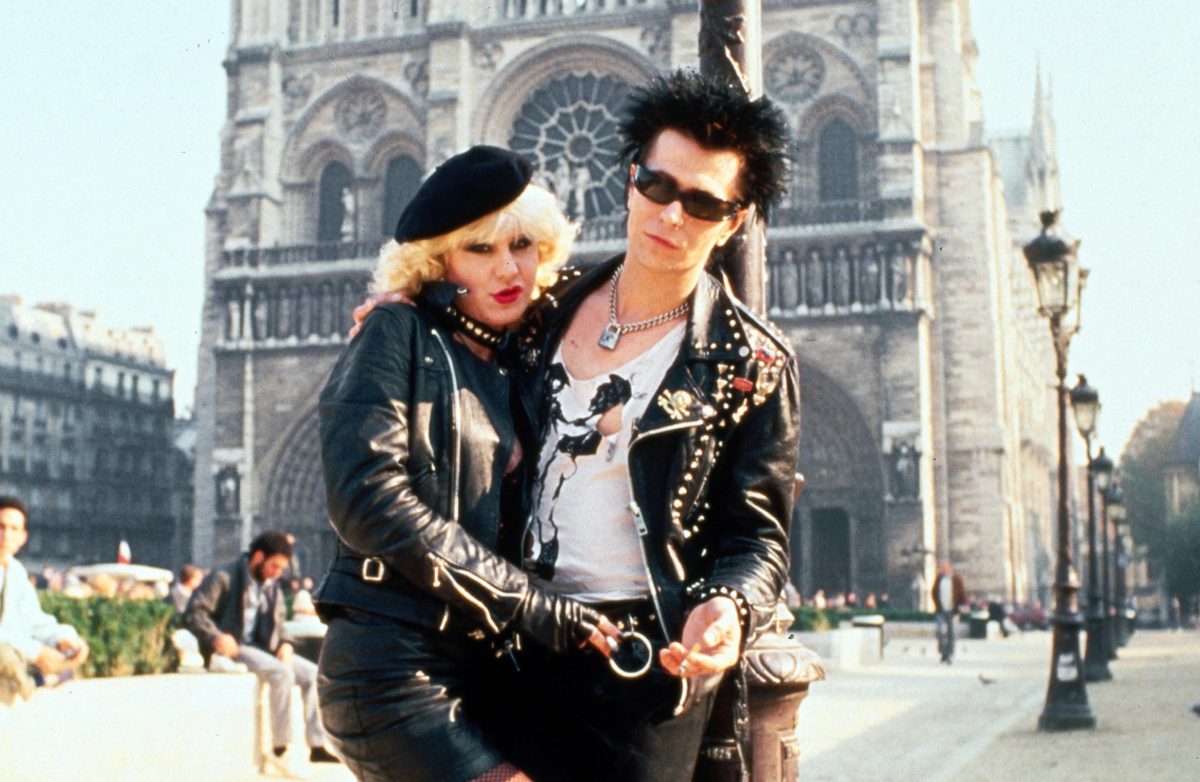 Still from Sid and Nancy showing a couple embracing in front of an old building
