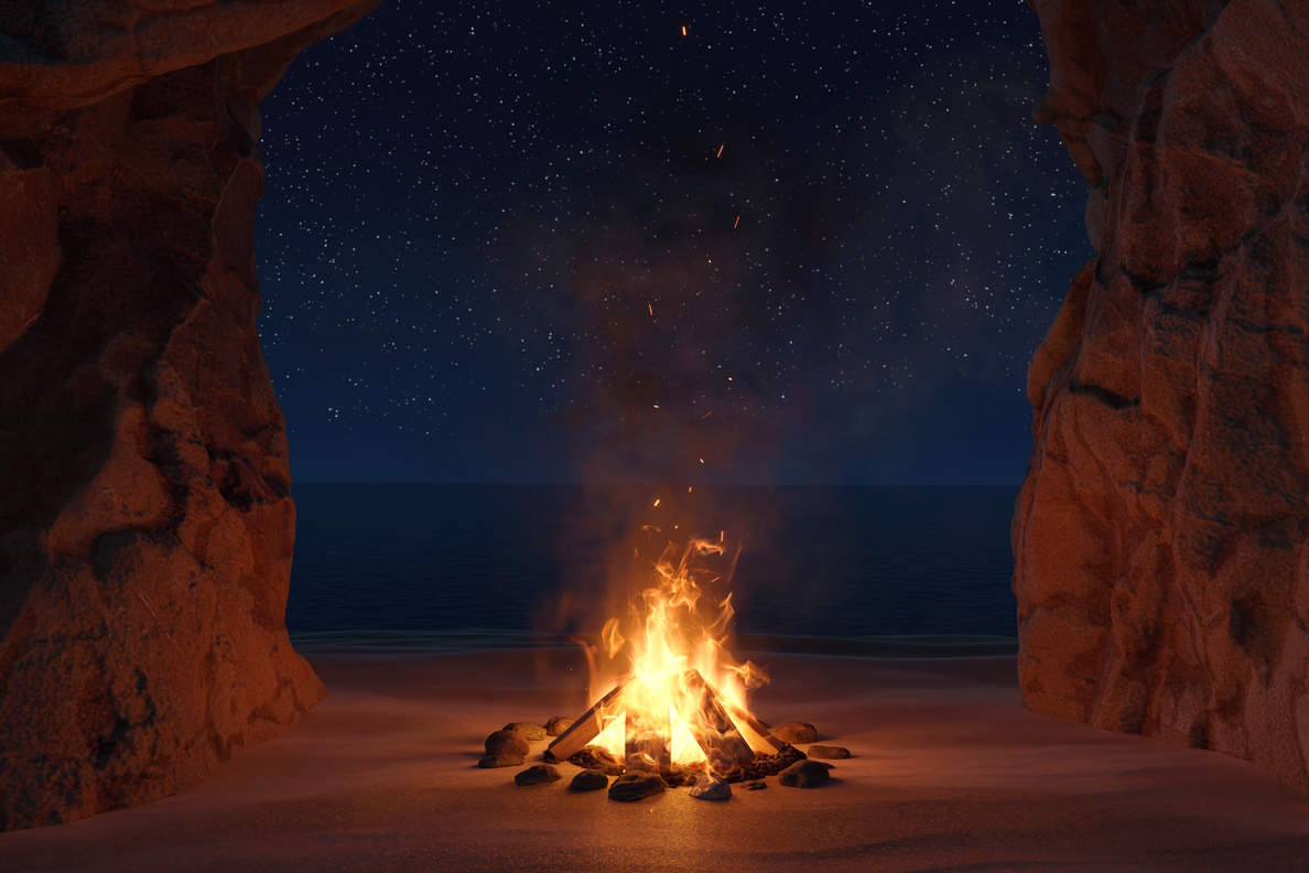 A campfire alight with a starry night sky in the background