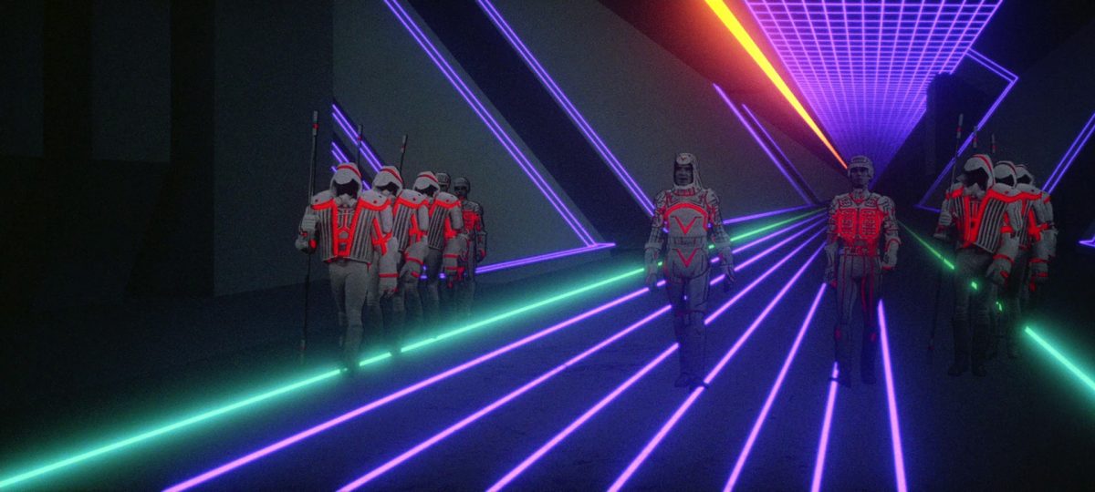 Still from Tron showing figures in helmets marching against a background of neon lines