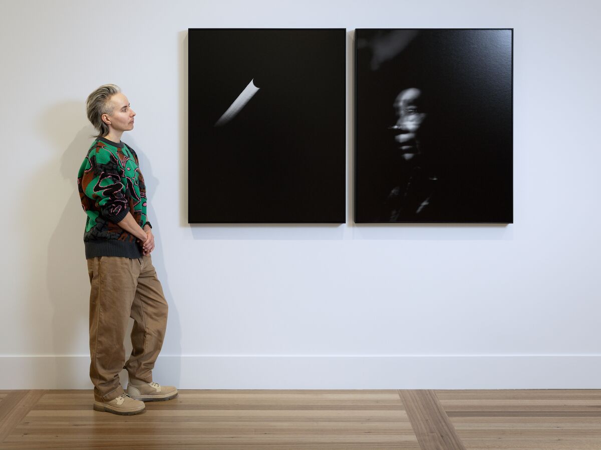 person stands looking at to two black and white photos