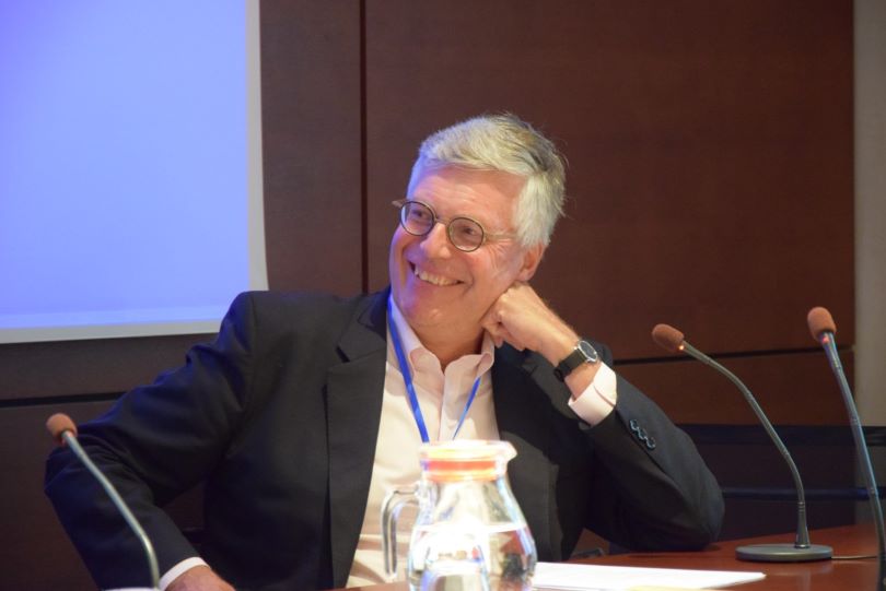 A photo of a man with glasses in a suit at a conference.