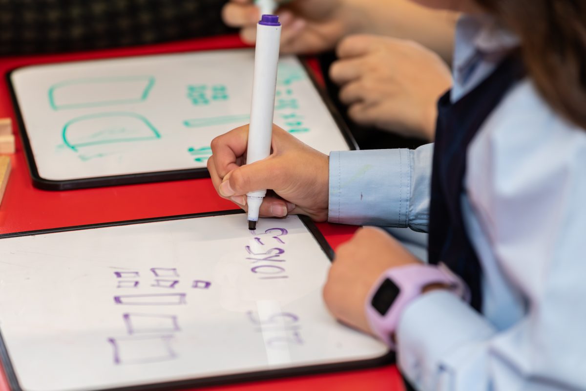 Child writing math on whiteboard