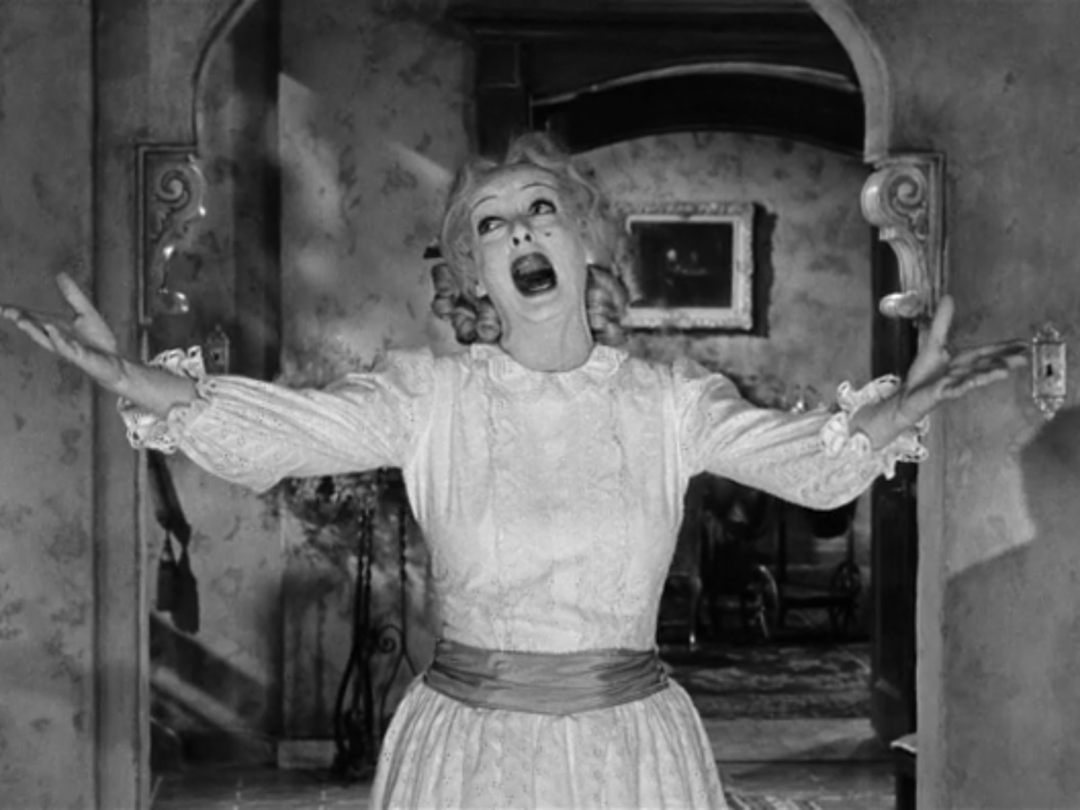 Black and white still from What Ever Happened To Baby Jane? showing a woman singing with hands out
