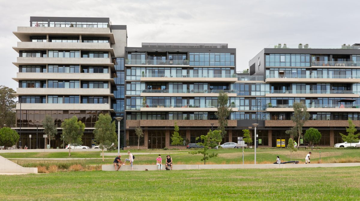 People enjoying parkland in front of residential apartment complex