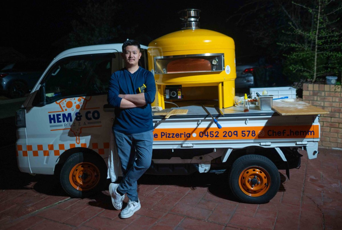 A man stands next to a truck with a pizza oven on the ute tray.