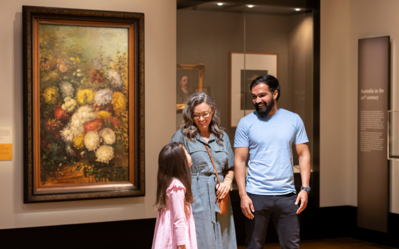 A man, woman and child in the Treasures Gallery at the National Library of Australia.