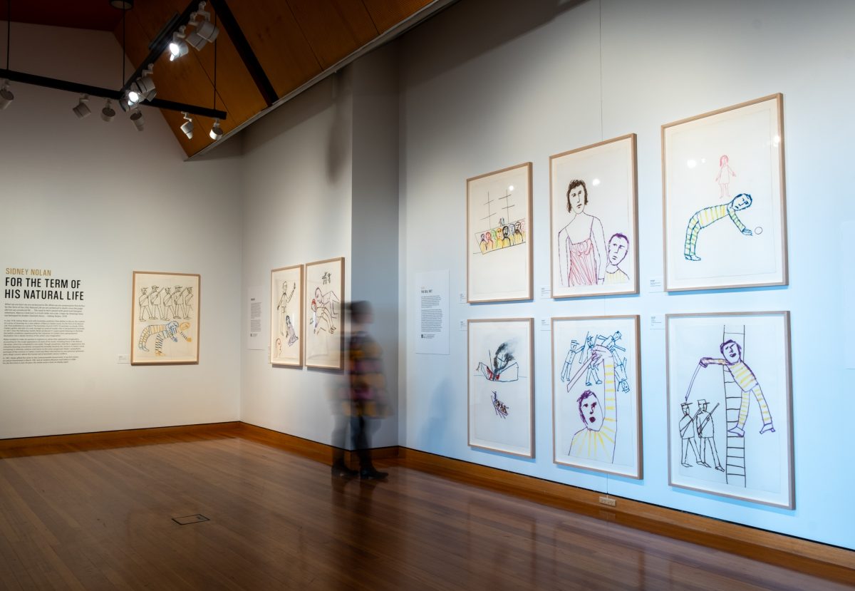 Woman viewing crayon artworks by Sidney Nolan in the CMAG exhibition For the Term of His Natural Life