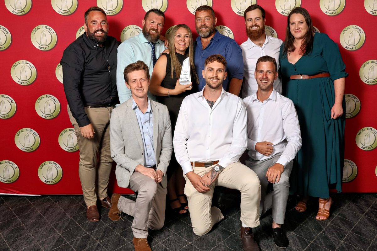 a group of people smiling with one person holding an award