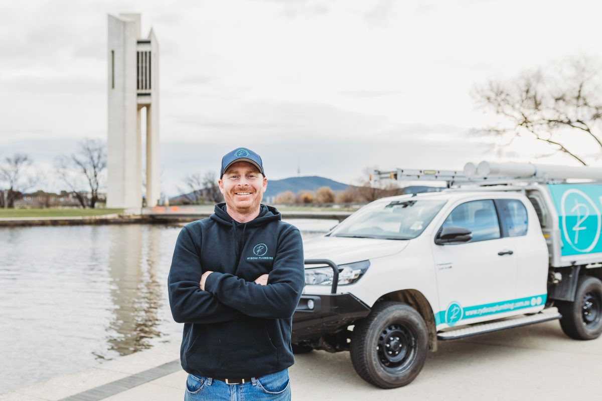 a man standing with folded arms standing in front of a work truck parked at the Carillon