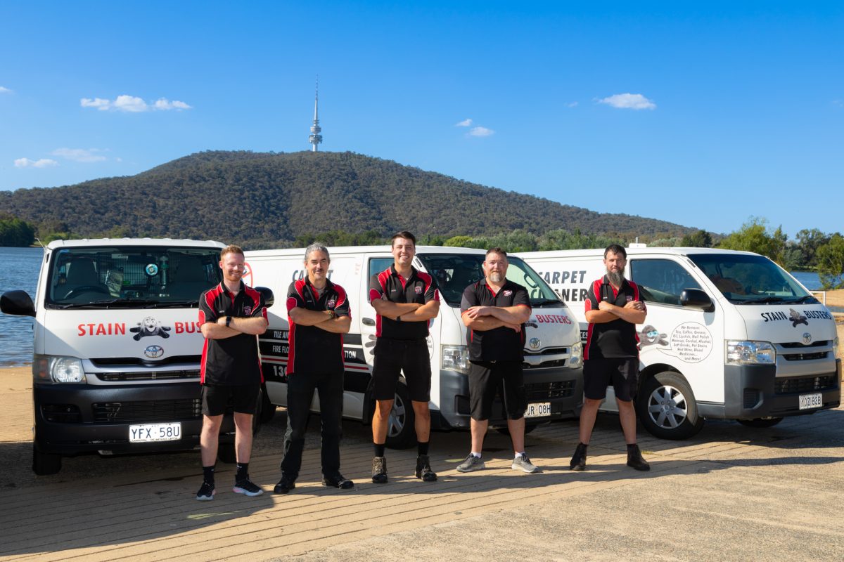 5 men standing in front of 3 vans, looking at camera