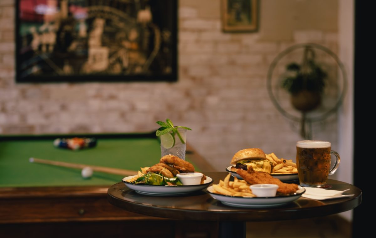 tray of plates with pub food and drinks in front of a pool table