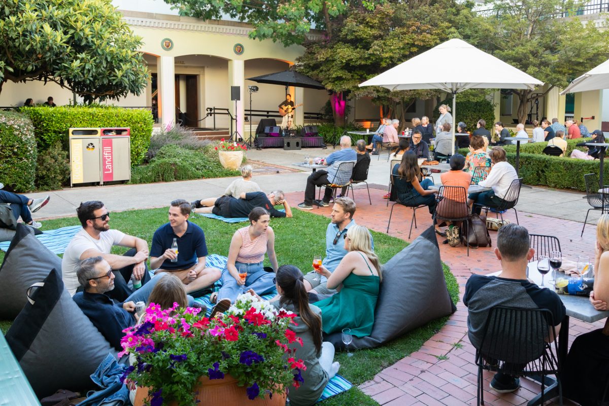 People enjoying drinks outside in a large courtyard whilst listening to live music