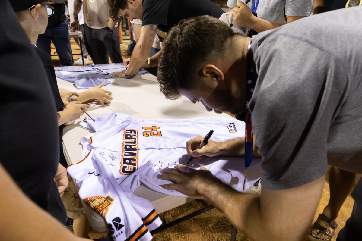 man signing a baseball jersey