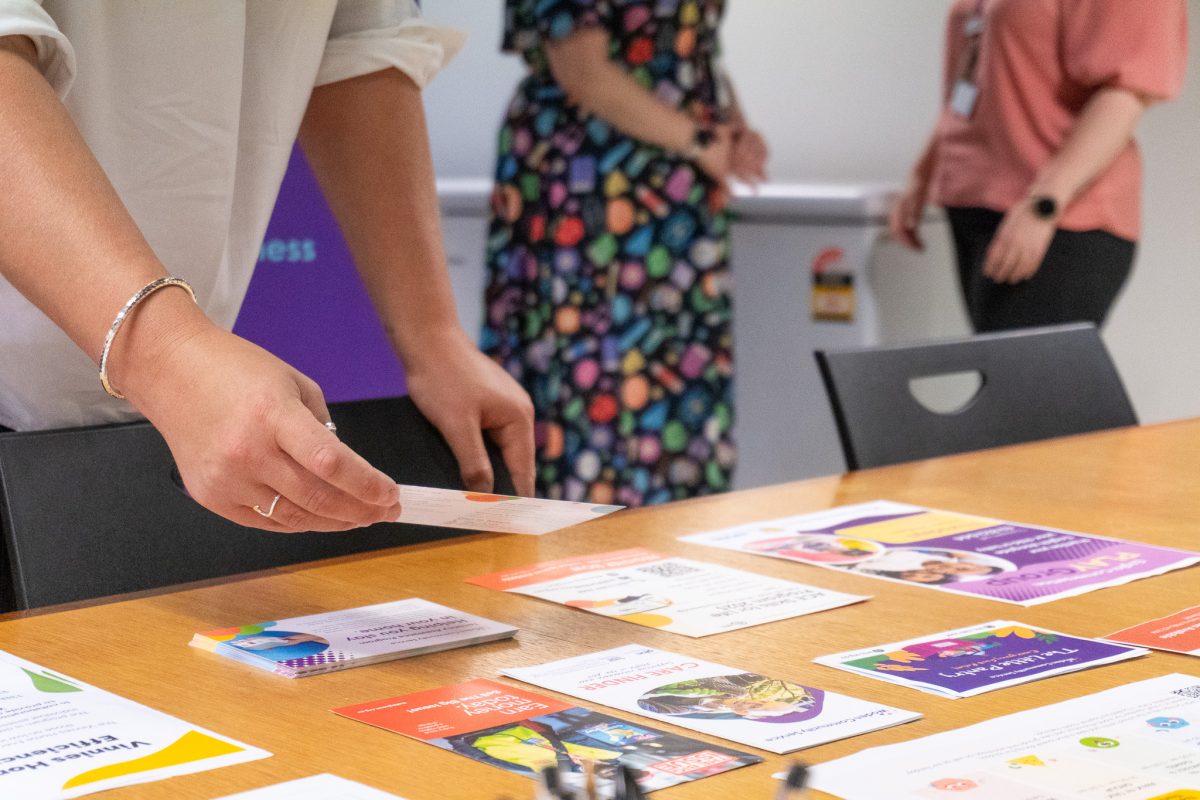 hands holding a brochure from a range of information sheets on a table