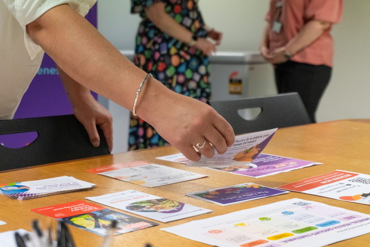 hands holding a brochure from a range of information sheets on a table