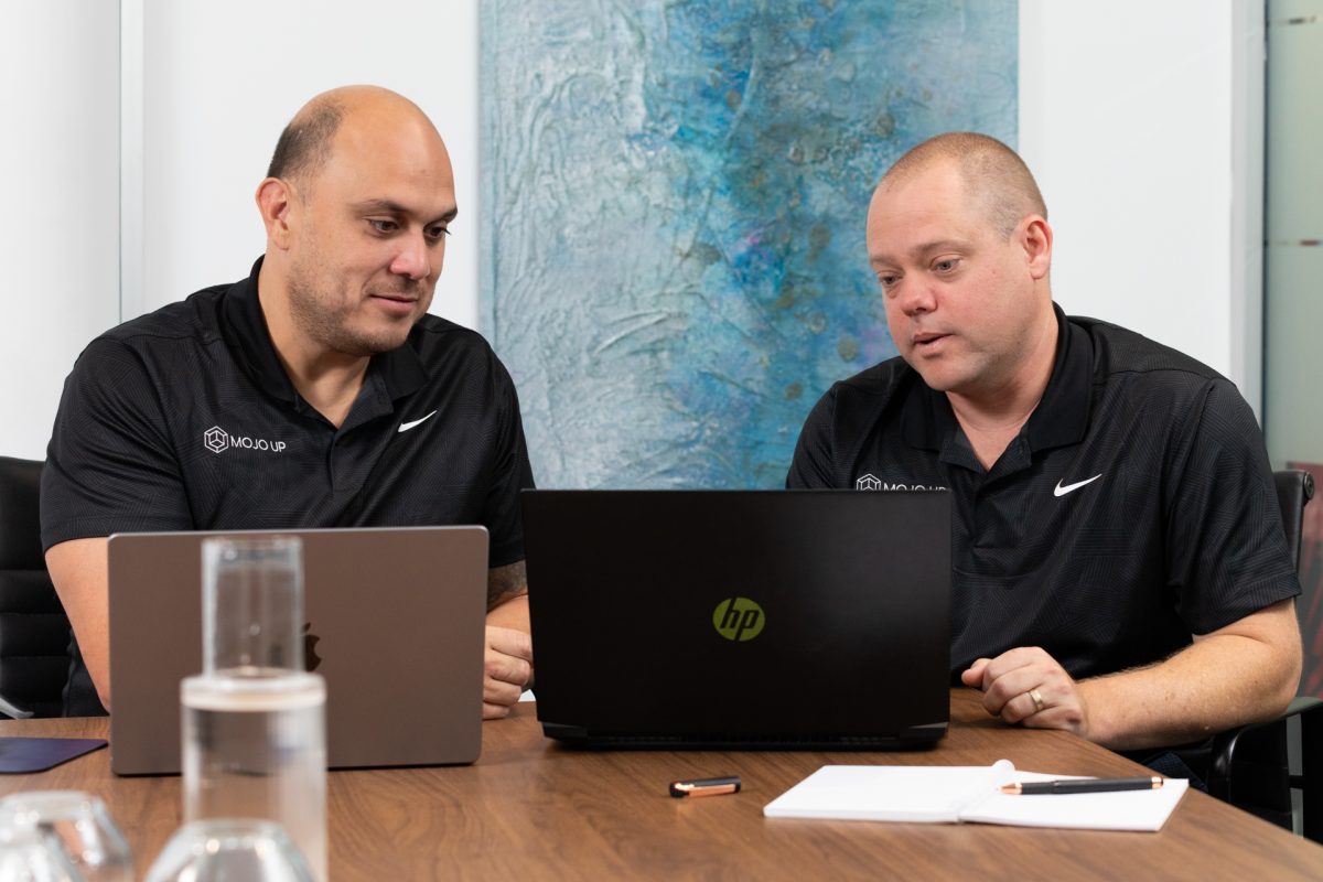 Mojo Up co-founders JP Simonis and Daniel Buchanan look at a laptop screen in an office