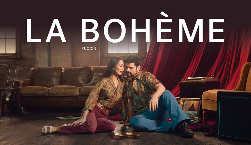 Photo of a couple, male and female sitting closely on the floor. Puccini’s La Bohème captioned on photo