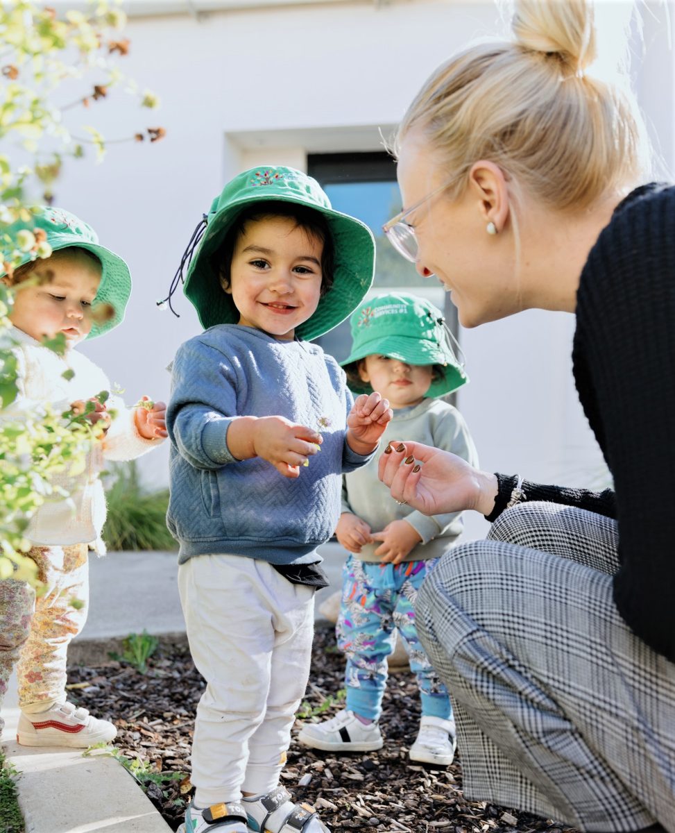 Child smiling to Camera with educator smiling at child