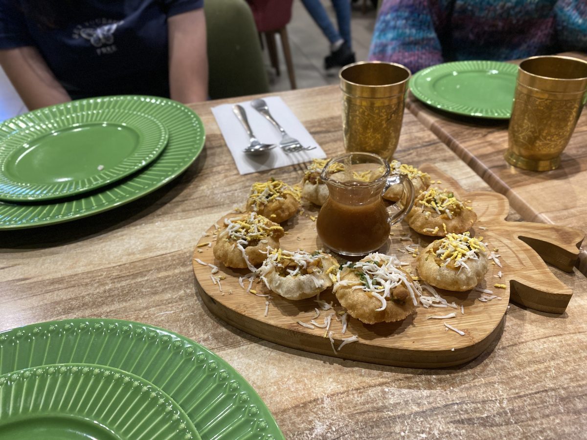 A wooden board with small snacks and a jug of tamarind.