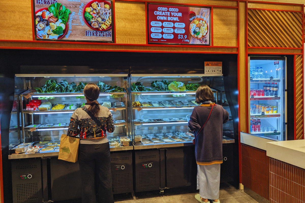 Two people serving their own ingredients at a Malatang restaurant.