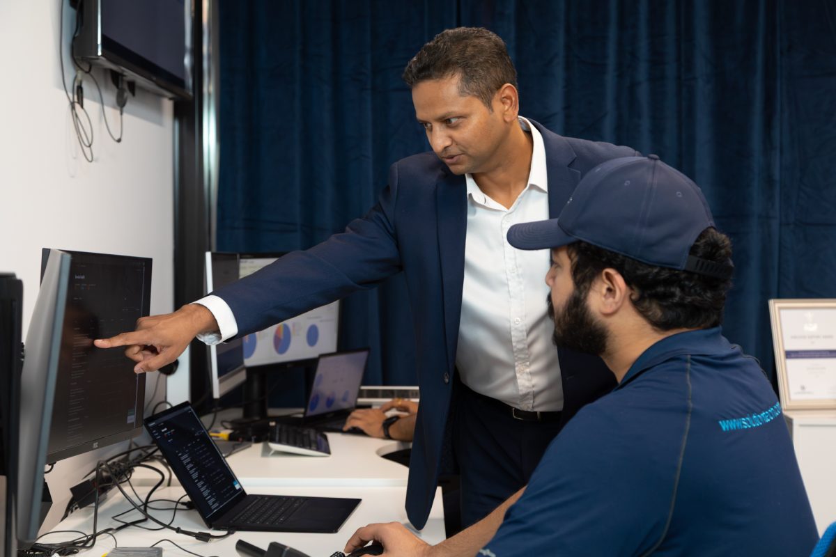 Roy Borekar of Solution Tech points at a screen in front of a colleague