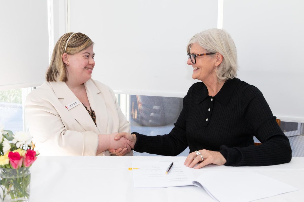 Two people sitting at a table and shaking hands