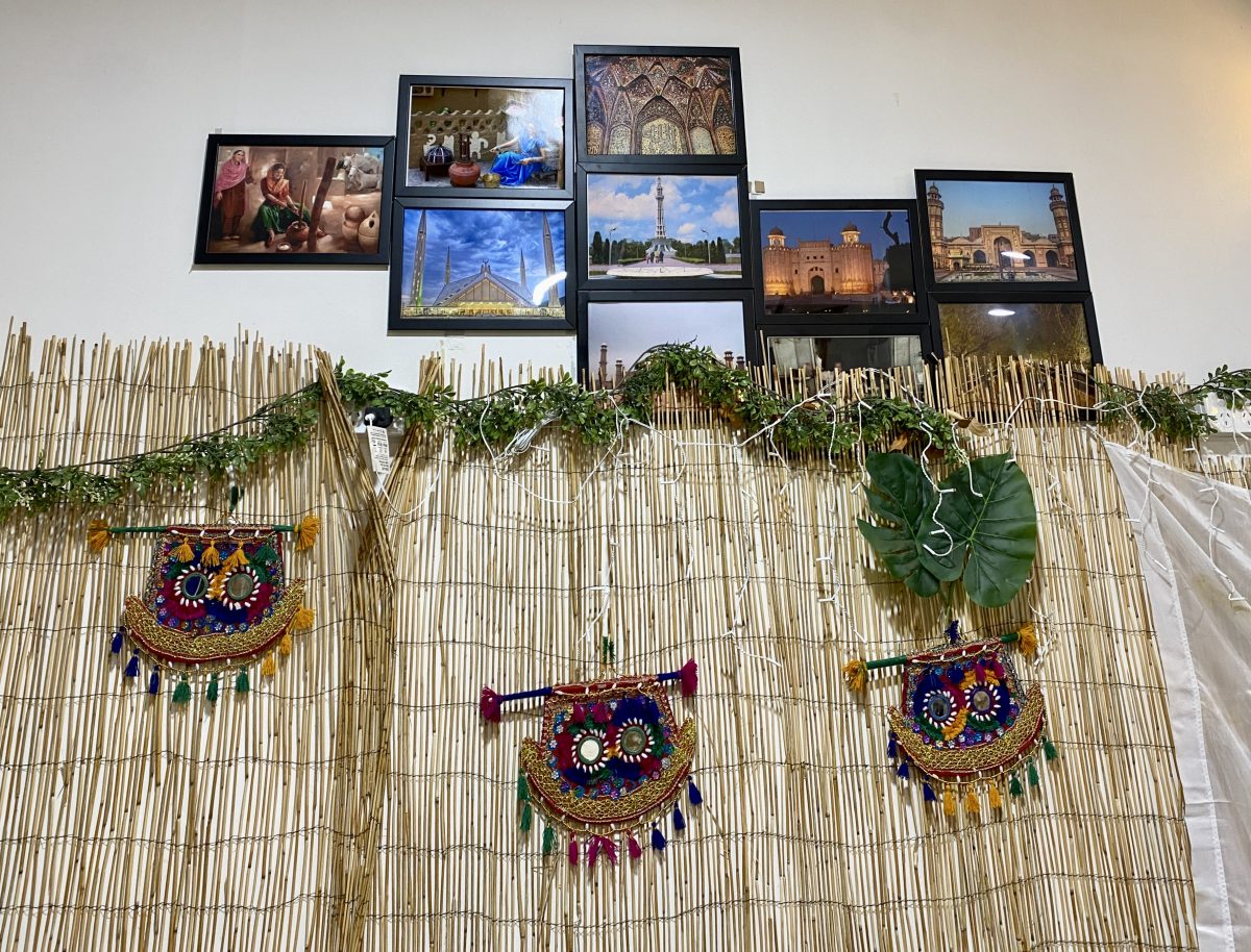 Masks on a wall in a restaurant with photos of Pakistani locations above.