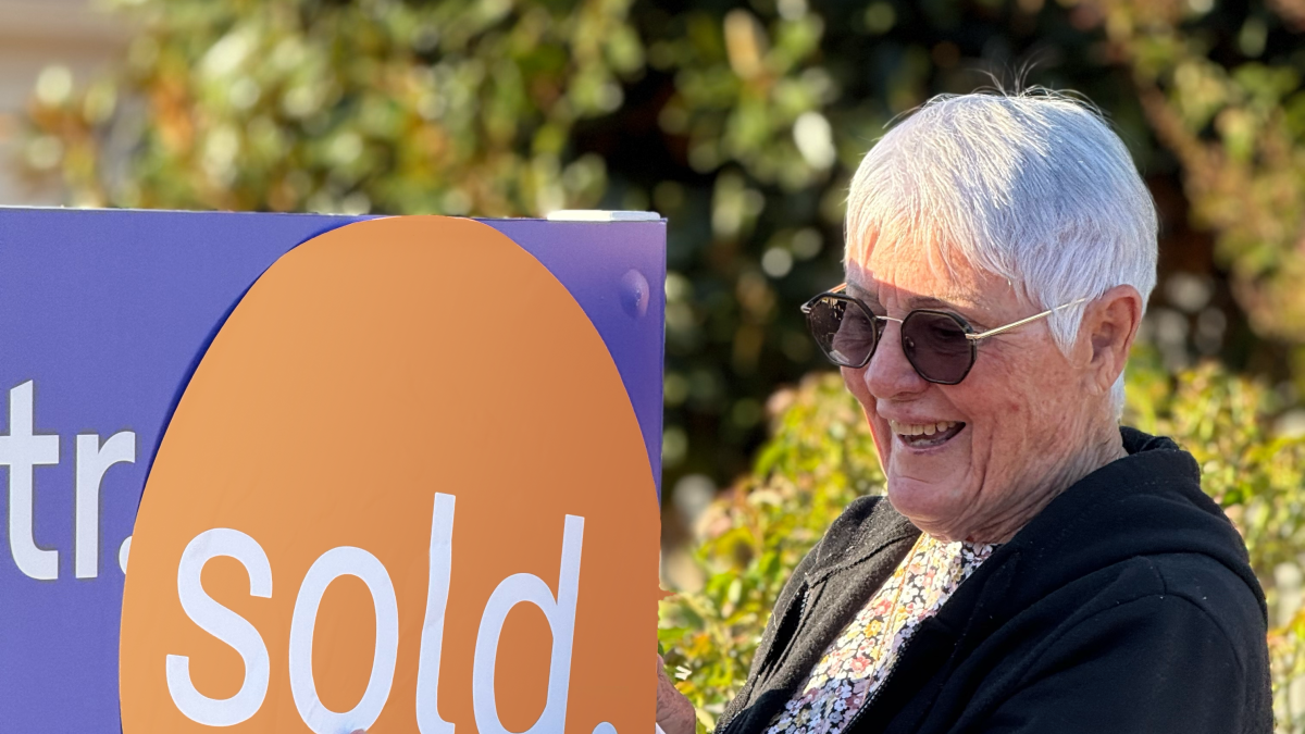 person smiling with sold sign