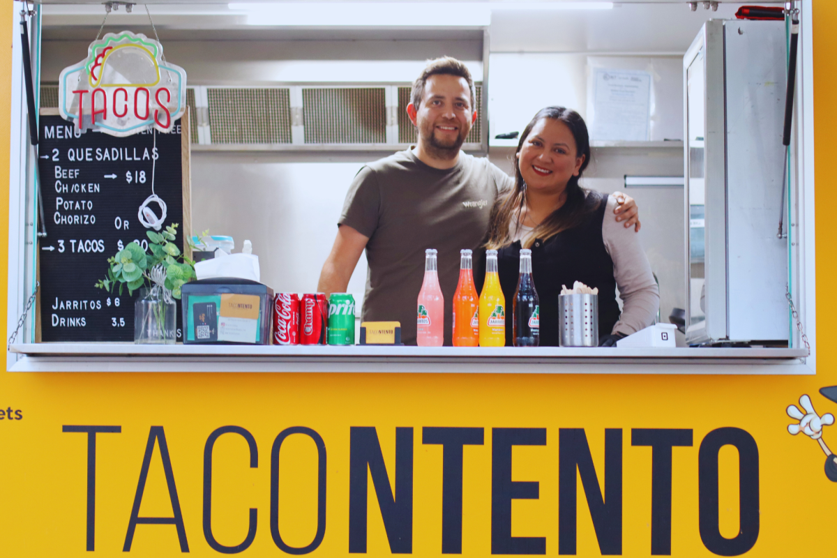 Man and woman stand in a food truck window.