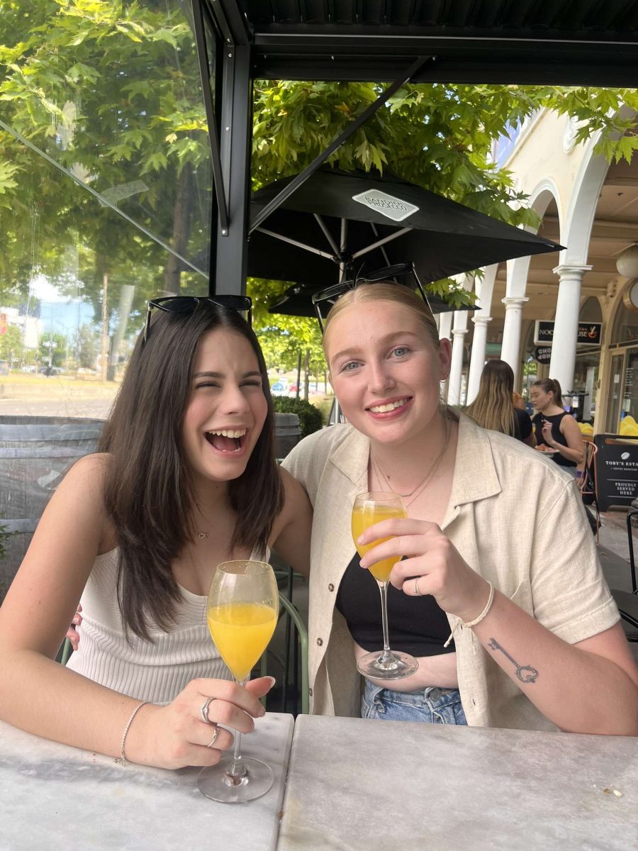 IBD advocate Madi with friend Amy celebrating Madi's 19th holding cocktails sitting at a table outside