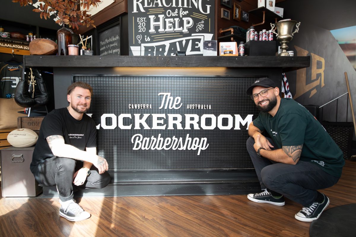 Two men in a barbershop posing for the camera