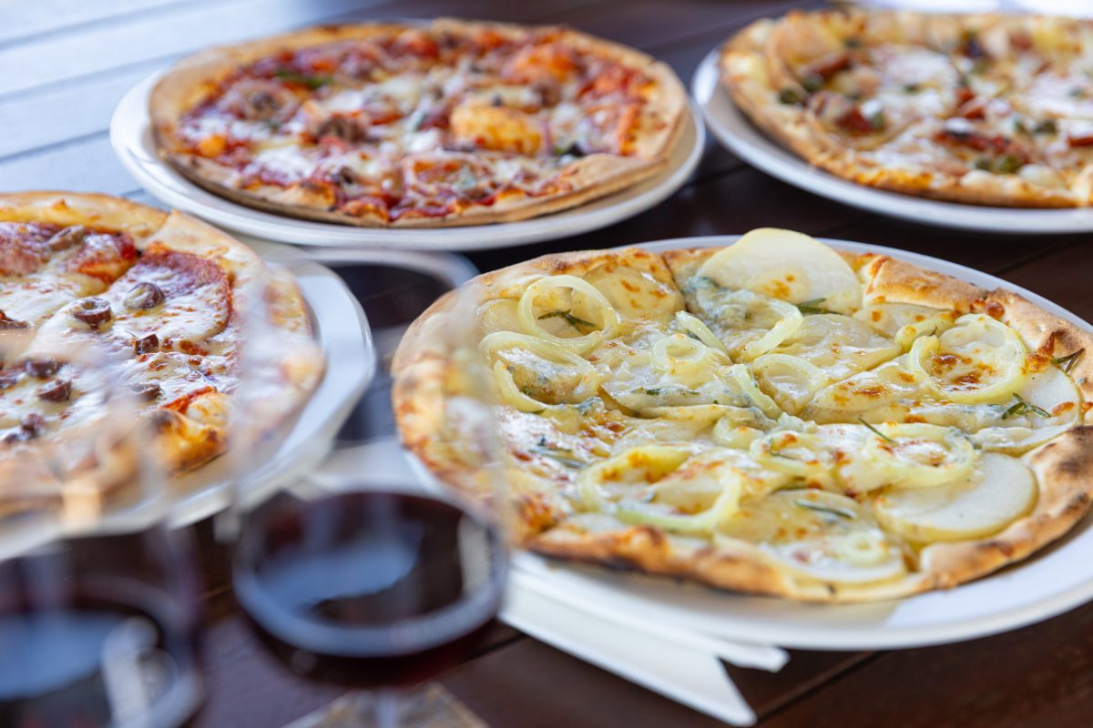 Four pizzas and red wine on a table