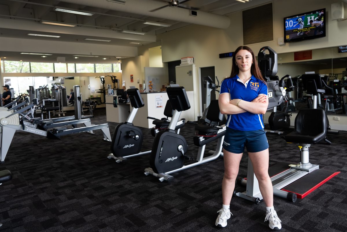 CIT fitness student Nikita Perry stands with her arms crossed at a gym