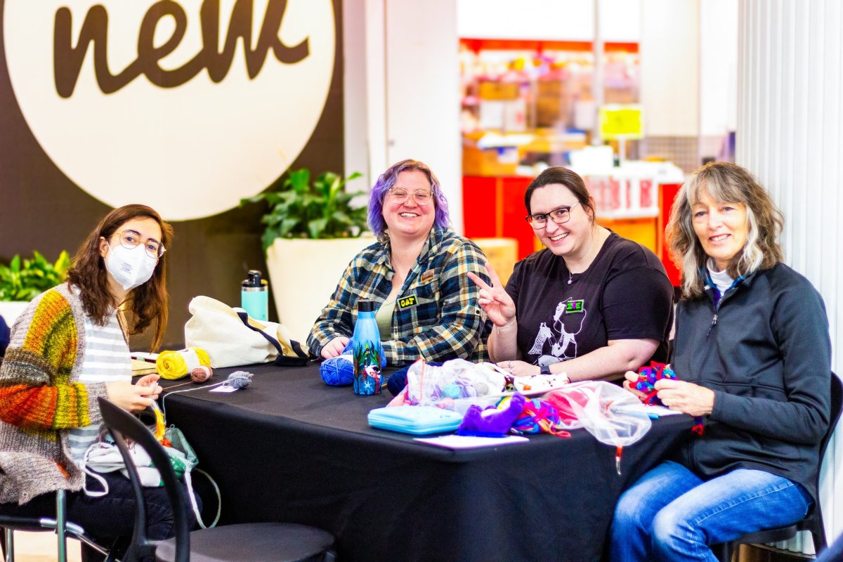a group of people sitting at a table knitting in the mall